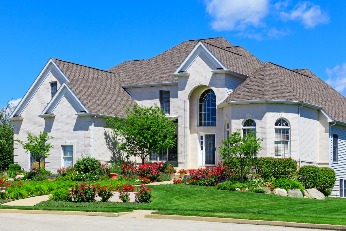 A neatly landscaped front yard with vibrant flowers and trimmed hedges, emphasizing the importance of understanding landscaping coverage in homeowners insurance.