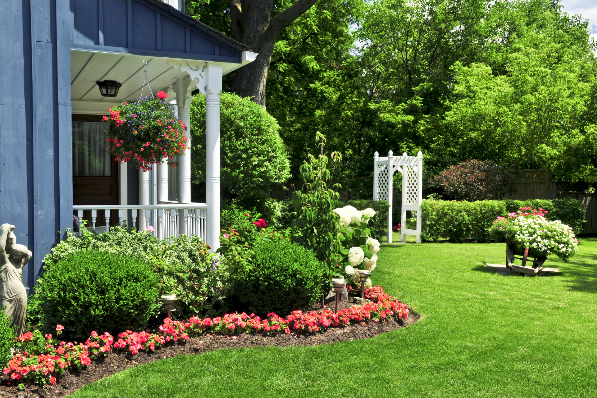A beautifully landscaped spring yard featuring colorful blooming flowers, lush green grass, and neatly trimmed hedges