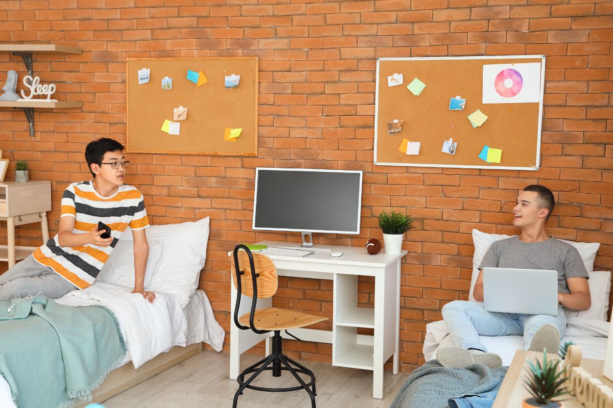 Two college roommates discussing safety tips in their dorm room, with one holding a safety checklist and the other nodding in agreement