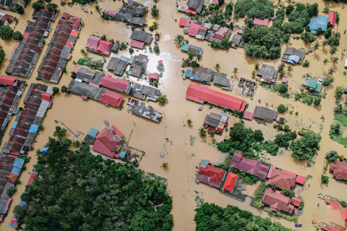A suburban home surrounded by heavy rain and rising floodwaters, highlighting the importance of spring flood preparation.