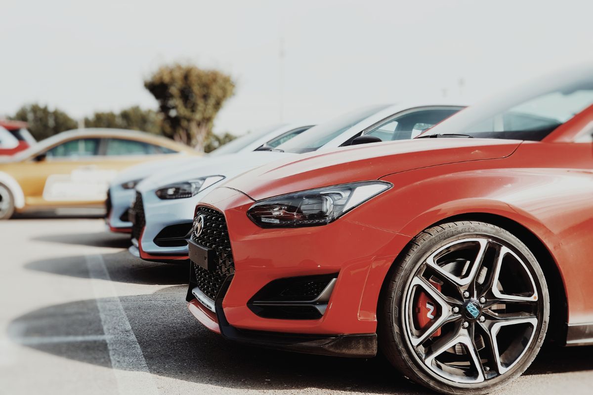 Driver checking tire pressure and using sunshade as part of smart car safety tips for summer heat protection.