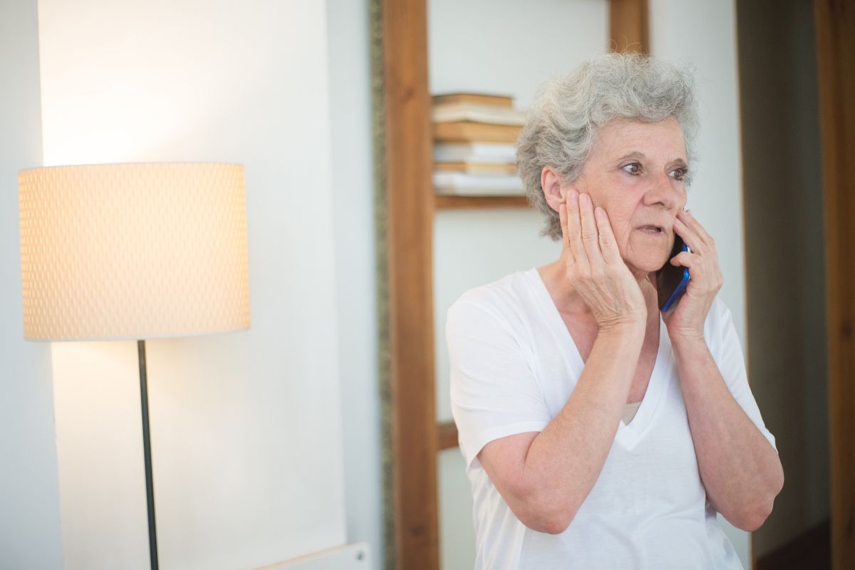 An elderly person holding a phone with a worried expression, suggesting they may be receiving a suspicious call related to an Inheritance Scam.