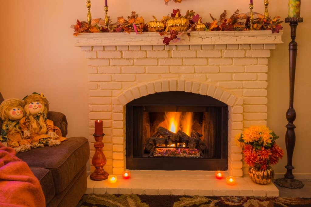 Close-up of a fireplace with protective screen and neatly stacked wood.