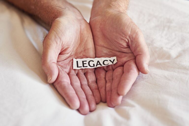 Hands of an elderly person gently holding a younger hand, symbolizing passing on love, security, and a lasting legacy through life insurance.