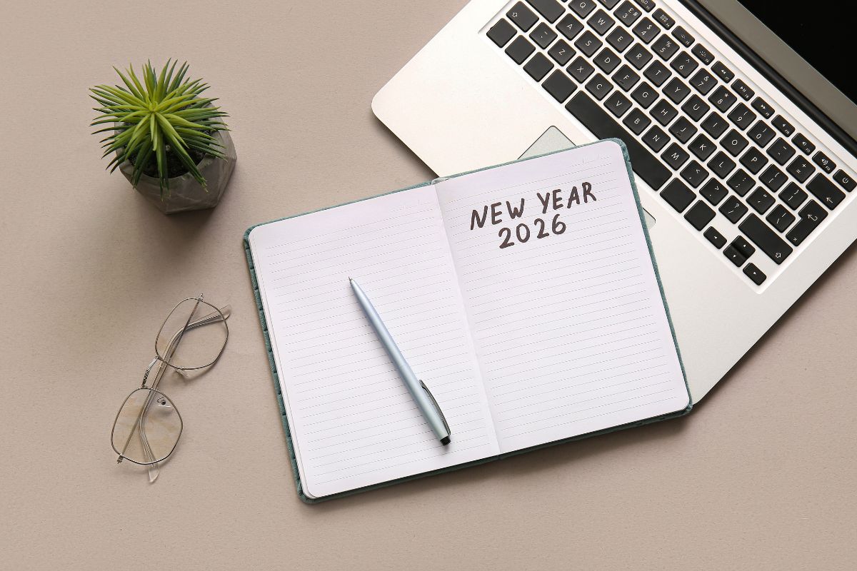 Person planning goals in a notebook with a calendar, representing practical steps for starting the new year strong.