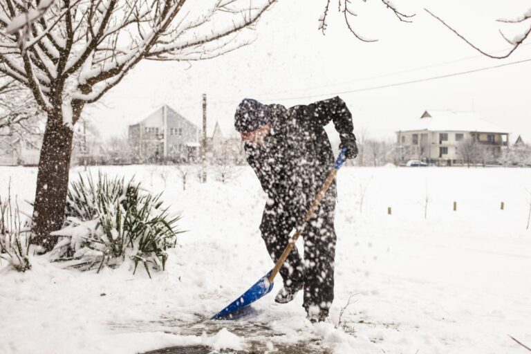 Person shoveling snow safely on a driveway during winter.