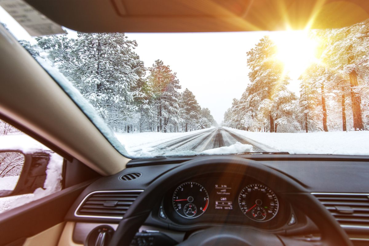 Driver gripping steering wheel while carefully navigating a car on an icy winter road.