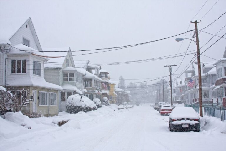 Blizzard covering houses and a car with heavy snow