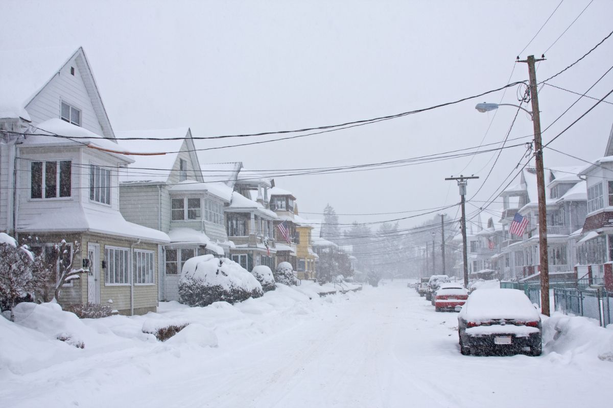 Blizzard covering houses and a car with heavy snow