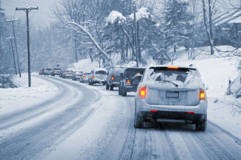 Car stranded on an icy road during an ice storm with snow-covered trees and low visibility conditions