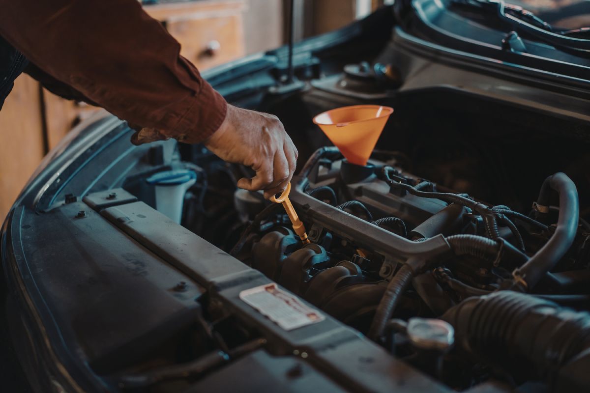 Person performing essential car maintenance by checking engine and fluid levels.