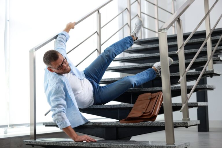 Employee placing a caution sign on a wet floor to help prevent slip and fall accidents at work.
