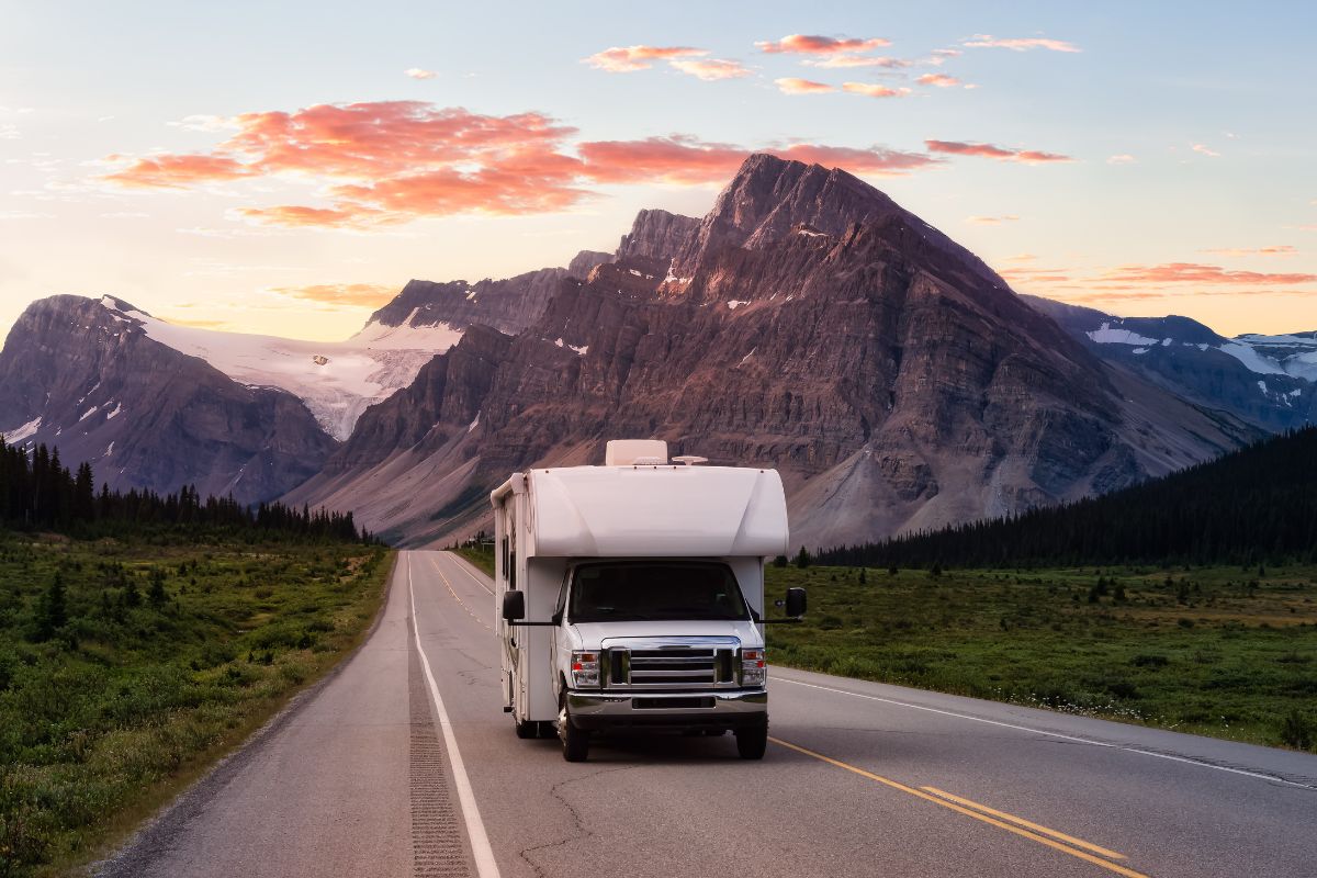 Illustration of an RV driving on an open road with coverage icons representing RV insurance protection such as collision, liability, and comprehensive coverage.