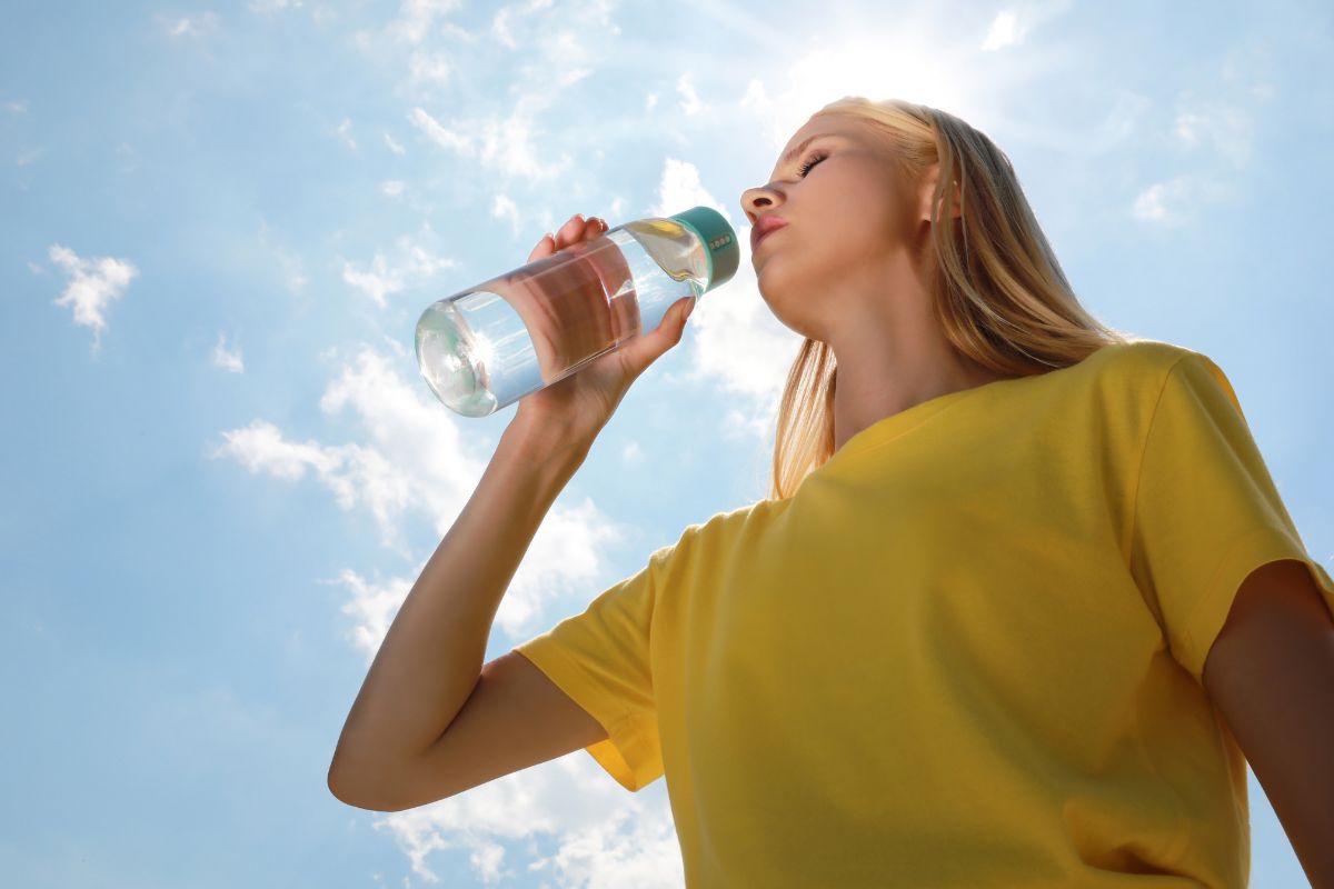 Family staying cool indoors during a heatwave while drinking water and using fans to prevent heat-related illness.