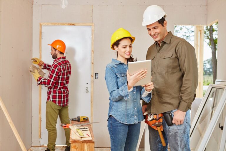 Homeowners reviewing renovation plans while discussing home improvement projects with a contractor inside a residential property.